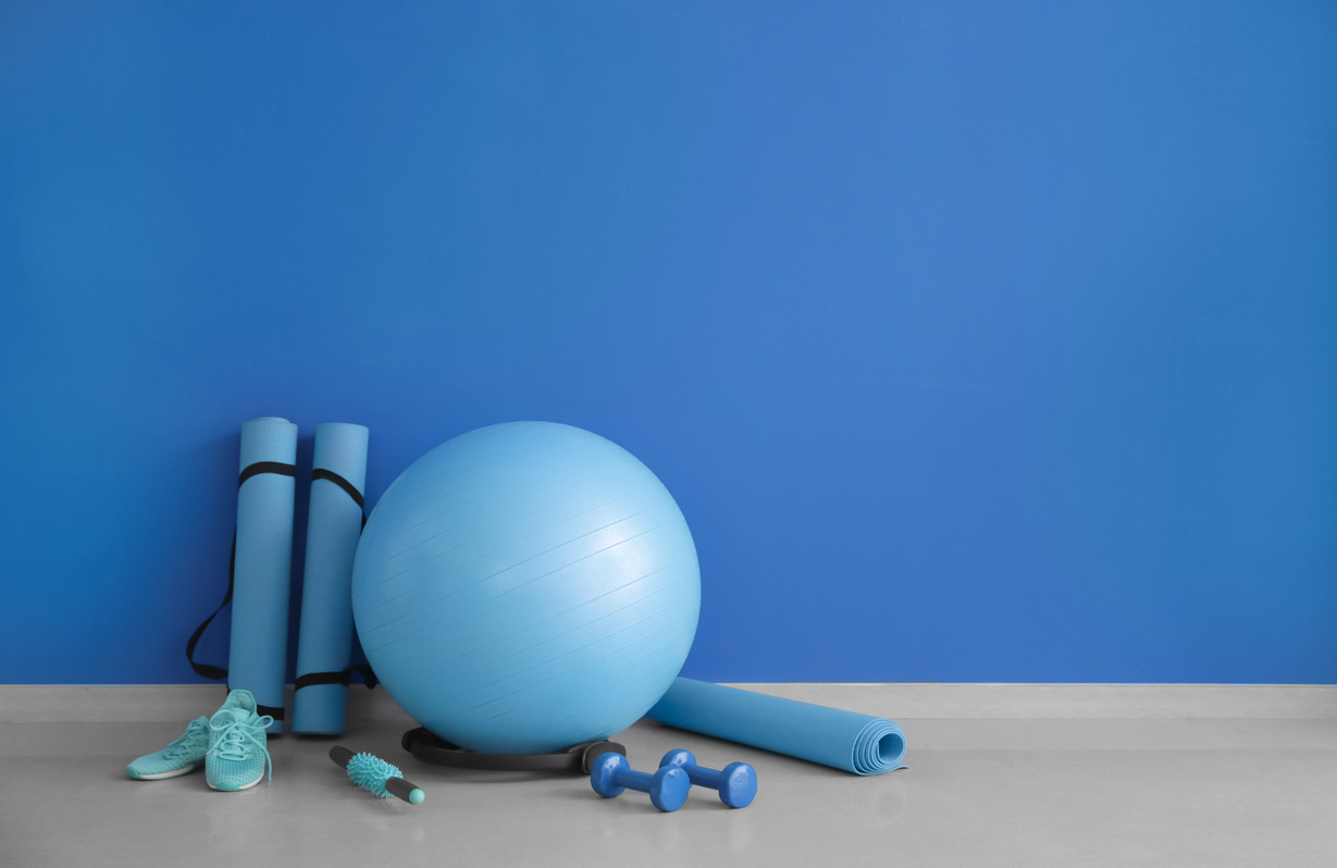 Set of Sports Equipment with Fitness Ball and Shoes near Color Wall